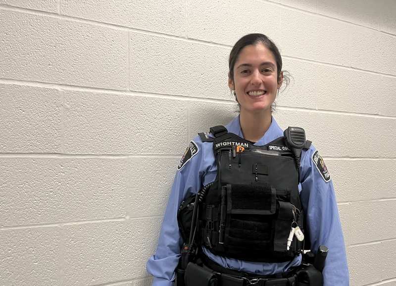 Special Constable Taylor Wightman stands against a white wall in the holding cells where she works. 